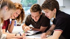 Happy young students studying together at table