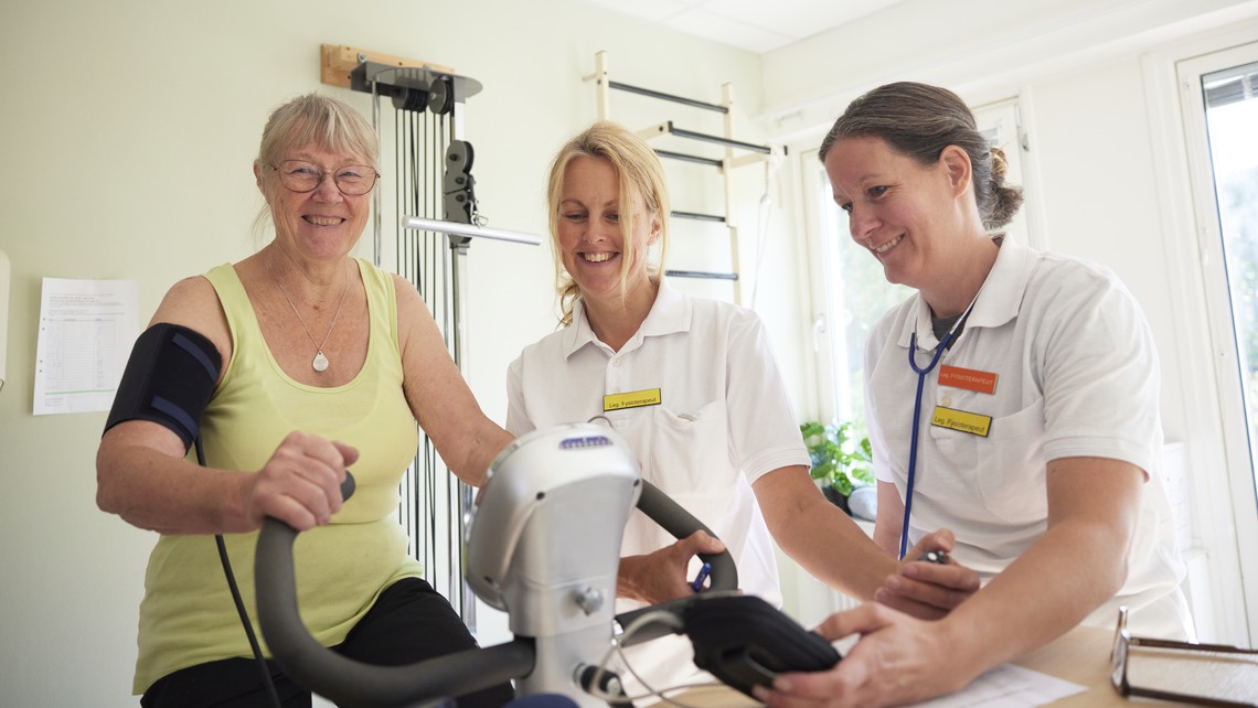 Patient på rehabilitering med fysioterapeut på motionscykel