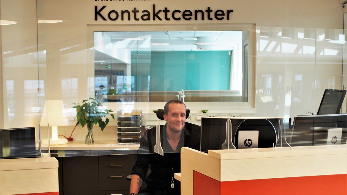 Man i svart skjorta sitter och jobbar vid informationsdisken i kommunens kontaktcenter.