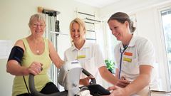Patient på rehabilitering med fysioterapeut på motionscykel