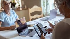 Äldre kvinnor sitter vid dator och mobiltelefon