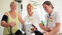 Patient på rehabilitering med fysioterapeut på motionscykel