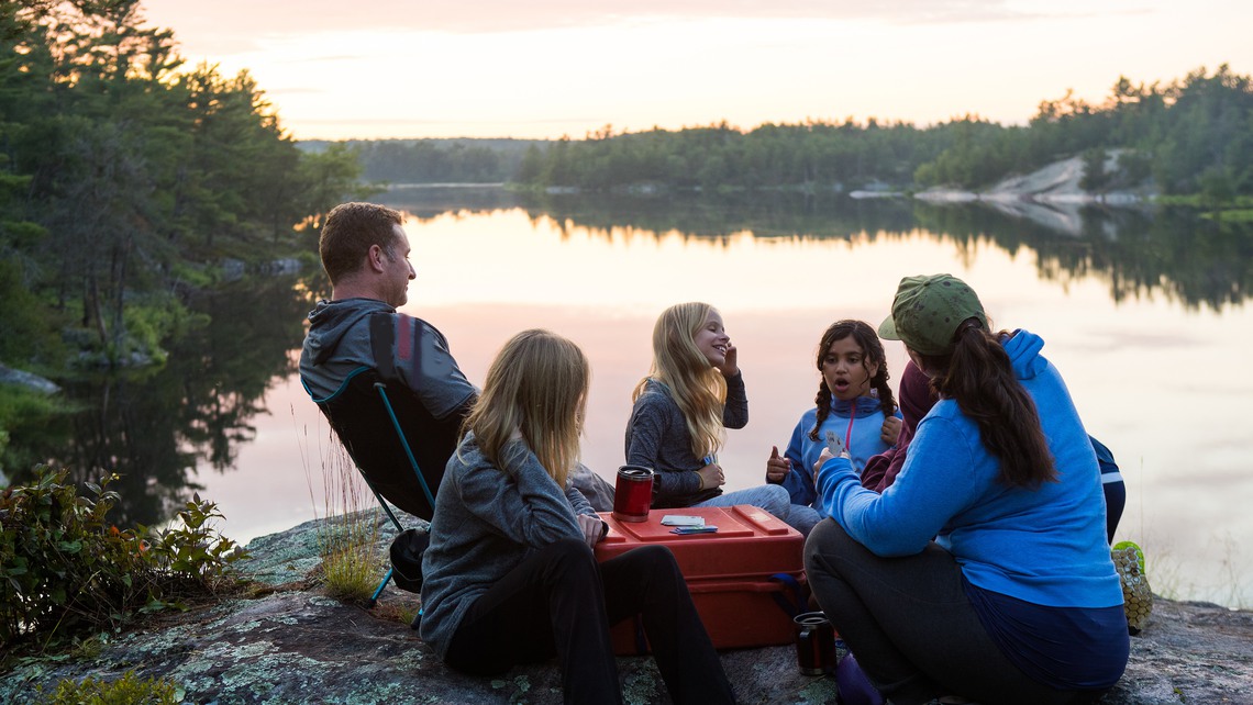 Kids play on the shore during a multi ethnic family canoe trip