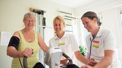 Patient på rehabilitering med fysioterapeut på motionscykel