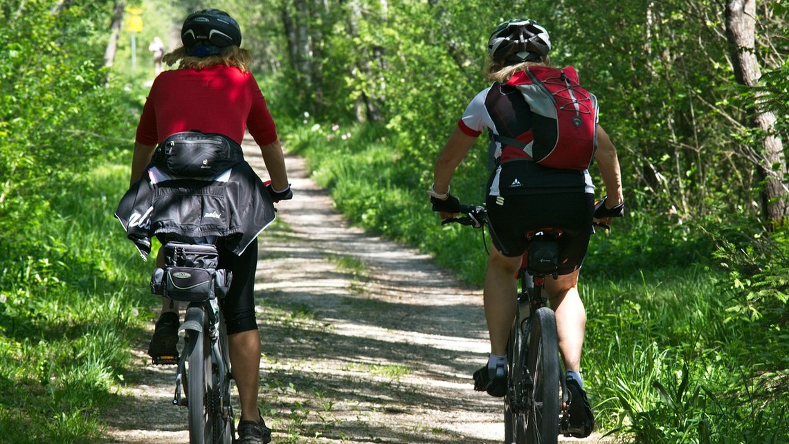 Två kvinnor cyklar mouintanbike i skogen. 