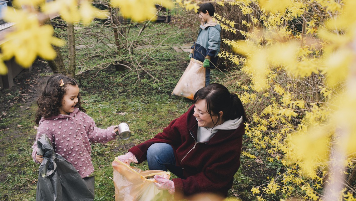 Happy daughter helping mother in collecting waste at backyard