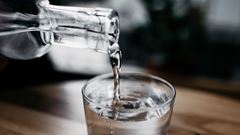 En kanna med vatten häller upp dricksvatten i ett glas. 