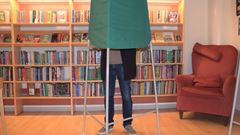 Ett valbås med en man som står bakom i ett bibliotek. 