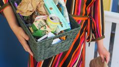 Kvinna i randig klänning håller en låda med återvinningsmaterial som förpackningar under armen.