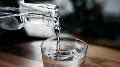 En kanna med vatten häller upp dricksvatten i ett glas.