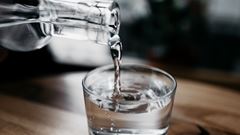 En kanna med vatten häller upp dricksvatten i ett glas. 