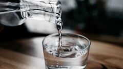 En kanna med vatten häller upp dricksvatten i ett glas.
