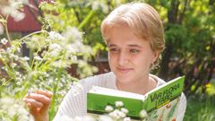 Elev tittar på växt och håller i en bok