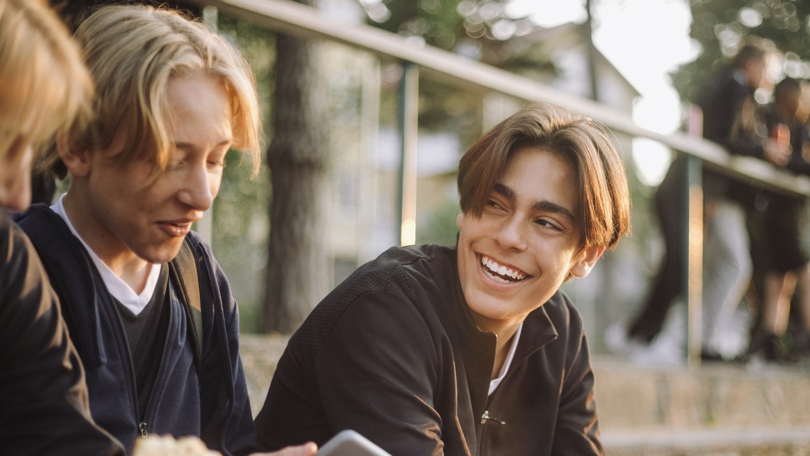 Glad ung kille håller i smartphone och pratar med kompisar