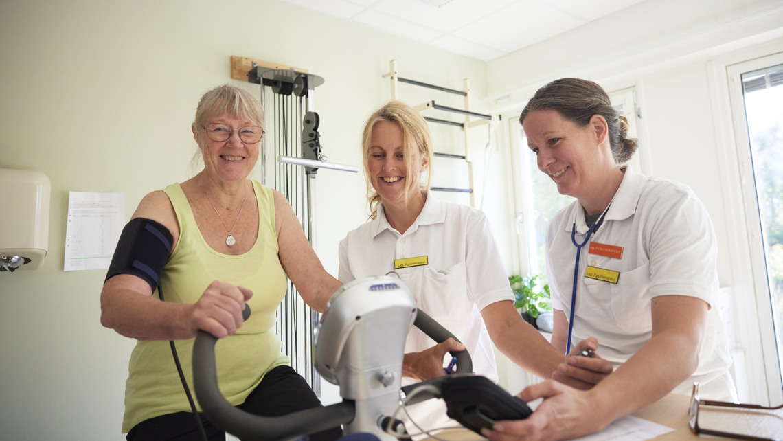 Patient på rehabilitering med fysioterapeut på motionscykel