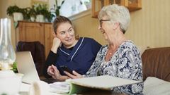 Hemtjänstpersonal hjälper äldre kvinna i hemmet