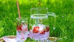 En tillbringare med vatten och jordgubbar står i gräset.