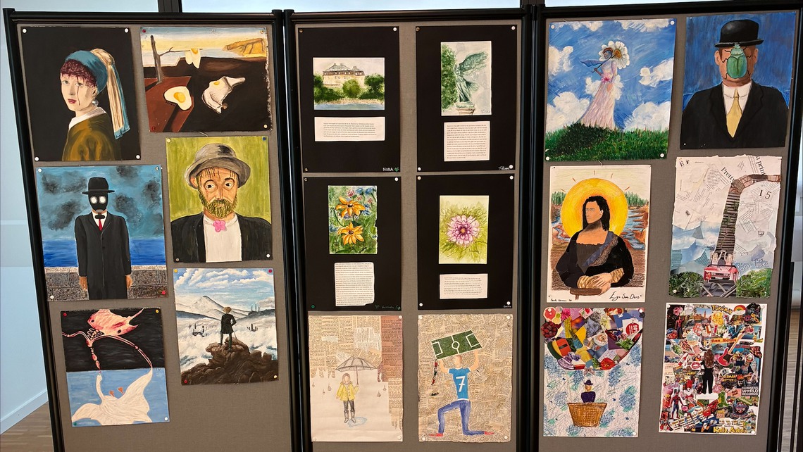 En sk&auml;rm med flera m&aring;lade konstverk som elever skapat.